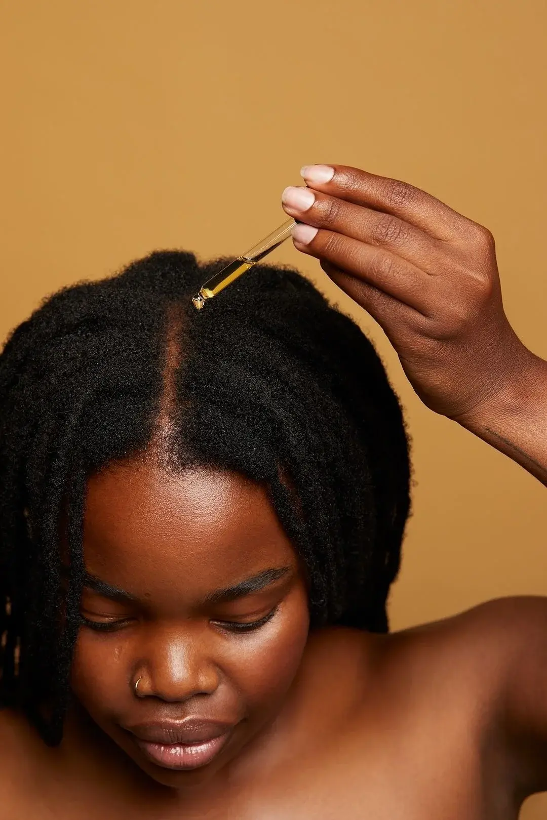 Woman applying Tribal Āfer 22 Essential Oils to natural hair